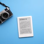 black SLR camera on and white e-book reader