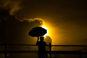 a person holding an umbrella in front of the sun