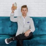 man in gray blazer raising drinking glass while sitting on sofa